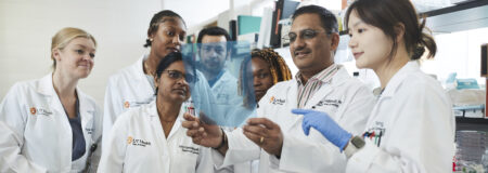 A doctor examines a paper with students.