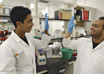 Arhan Rao high-fives a colleague in the lab.