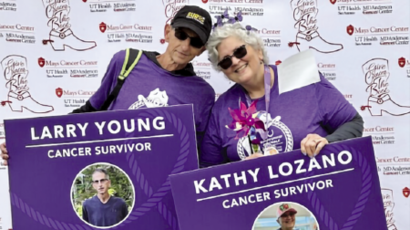 Two cancer survivors, Larry Young and Kathy Lozano, pose together holding purple signs that read their names and "CANCER SURVIVOR," against a backdrop of cancer organization logos.