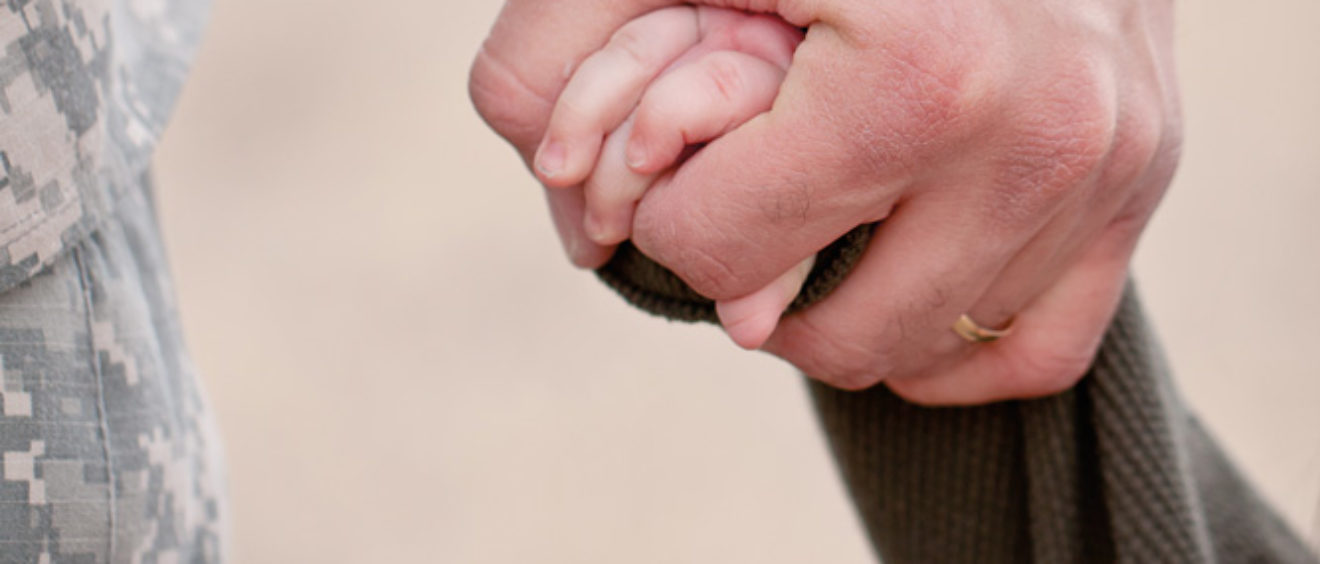 soldier holding kid's hand.