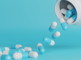 white and blue pills spill out of pill bottle