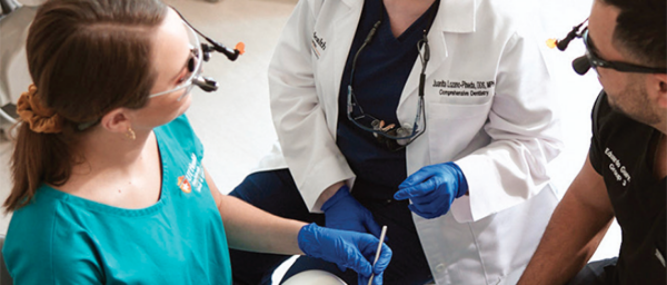 A dental faculty member works with dental students.