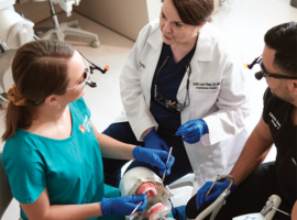A dental faculty member works with dental students.