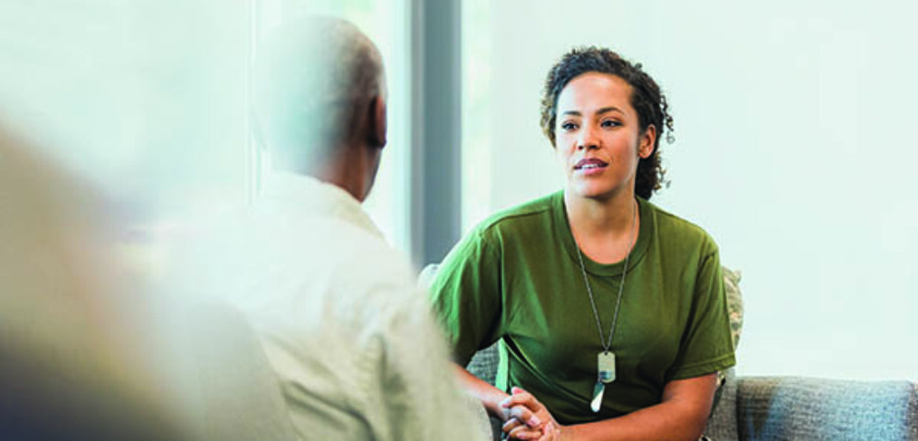 woman wearing military tags talking to a man.