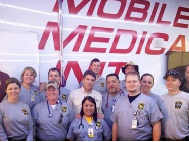 Several responders from the Texas Emergency Medical Task Force, including two from the UT Health Science Center, visit with Gov. Rick Perry in West following the fire and explosion at the fertilizer plant. Emily Kidd, M.D., is on the first row on the left and Todd Bergbacher, D.O., is third from the left in the back row next to Gov. Perry, who is wearing the tan shirt.
