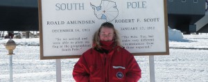 Desiree Dingman stands in front of the sign that designates the geographic South Pole.
