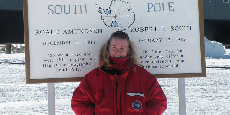 Desiree Dingman stands in front of the sign that designates the geographic South Pole.