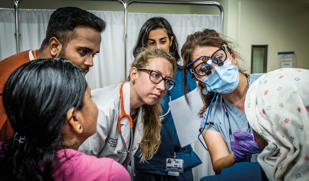 Nursing student Alizain Maneshia (top left), medical student Nichole Michaeli (with stethoscope) and dental student Peggah Hammat observe as Dr. Farokhi, dental faculty adviser to the clinic, points out a dental problem in a patient.