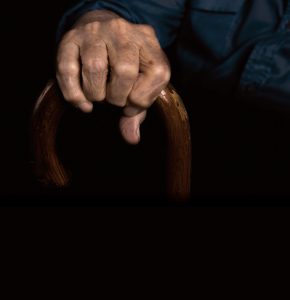 elderly hand holding a cane.