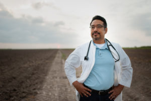 Joel Torres, M.D., stands on a dirt road in the Rio Grande Valley.