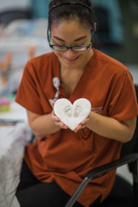 nursing student holding plaster heart with footprints
