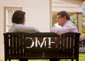 Mariah Newton and Mark Soucy, Ph.D., RN, APRN, FAANP, talk on an outdoor bench.