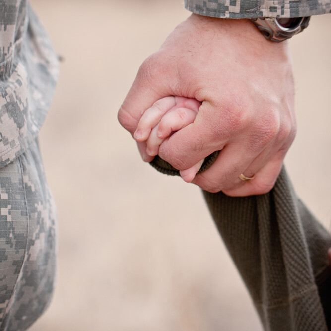 soldier holding kid's hand.