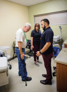 physical therapy students work with a patient and his cane