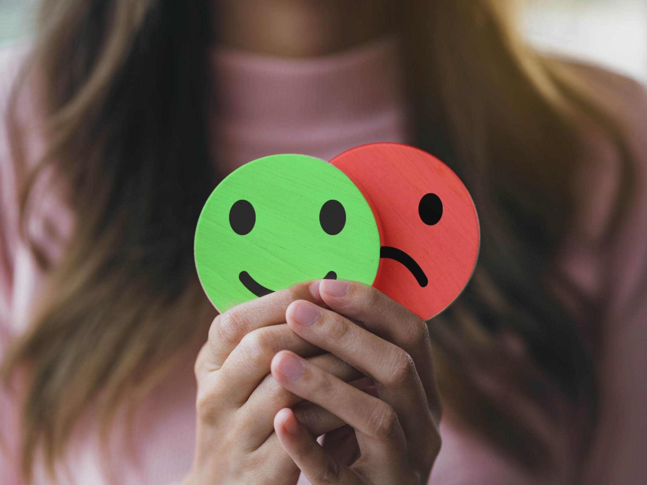 Photo showing woman holding smile and frown cutouts