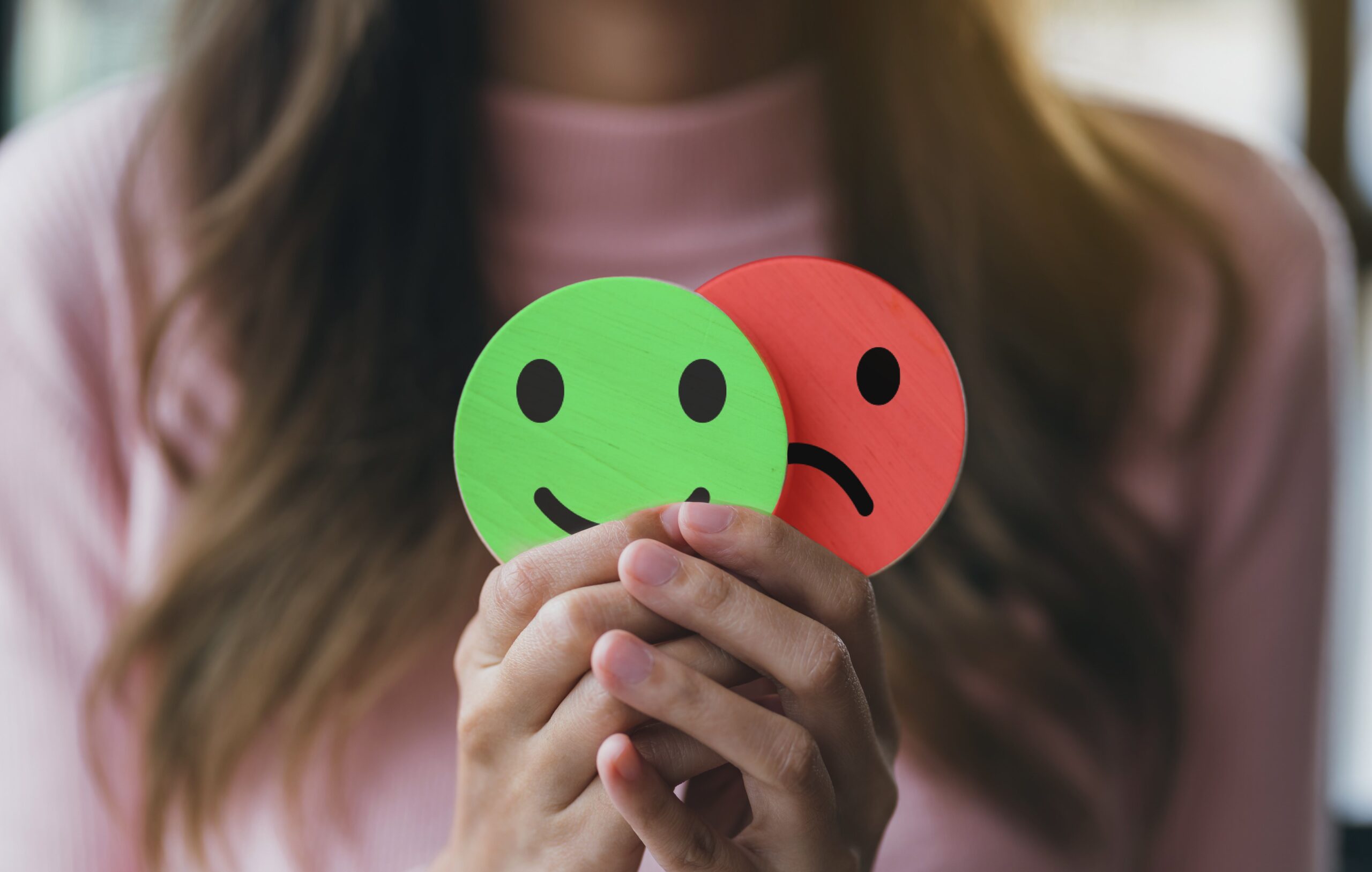 Photo showing woman holding smile and frown cutouts