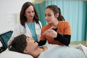 Nurse student practices checking vitals on manikin