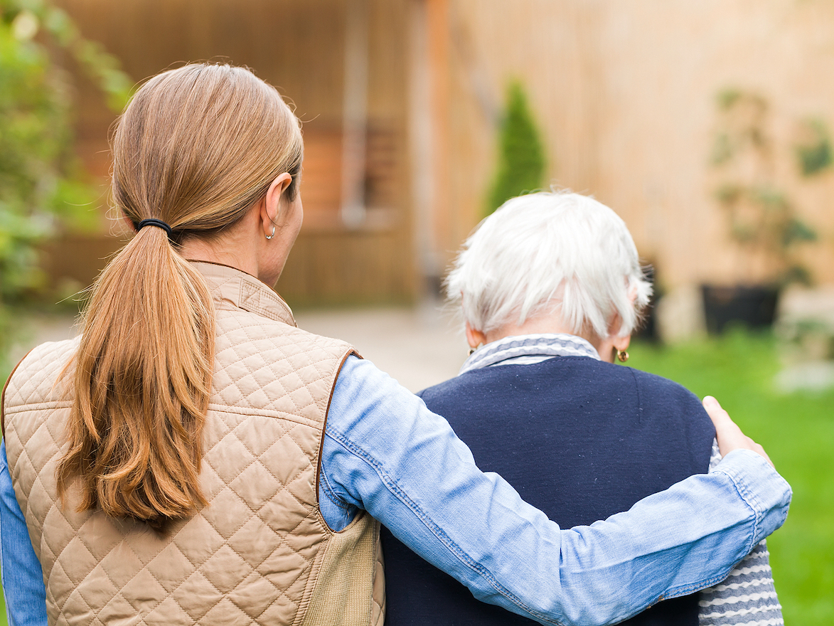 Young carer walking with the elderly woman in the park