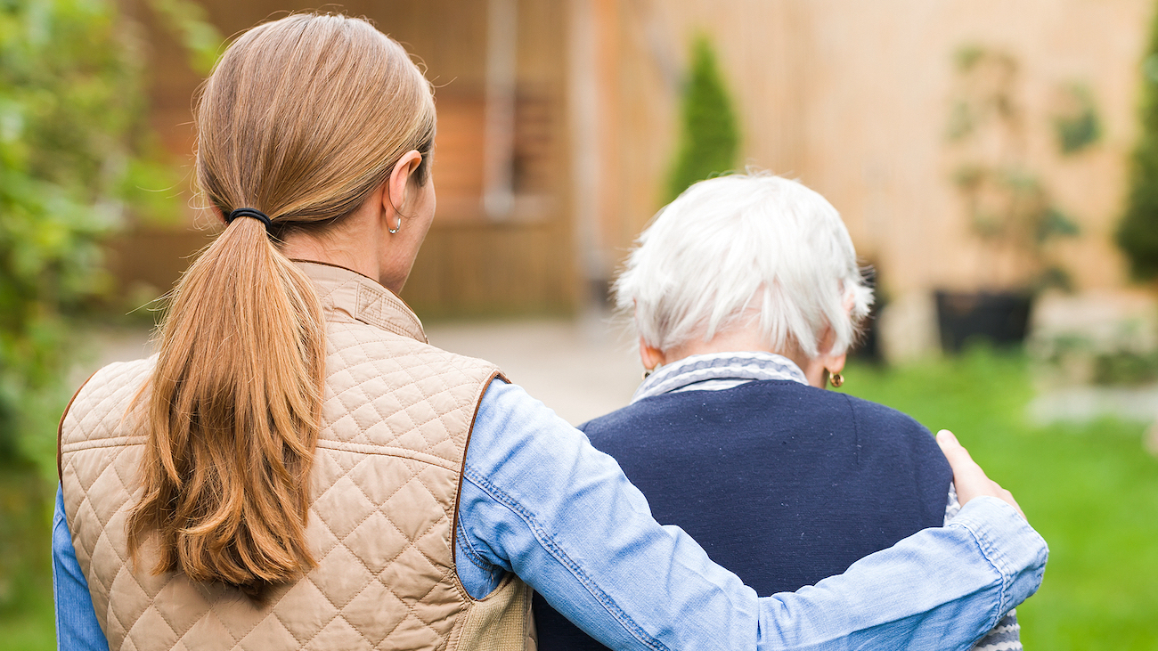 Young carer walking with the elderly woman in the park