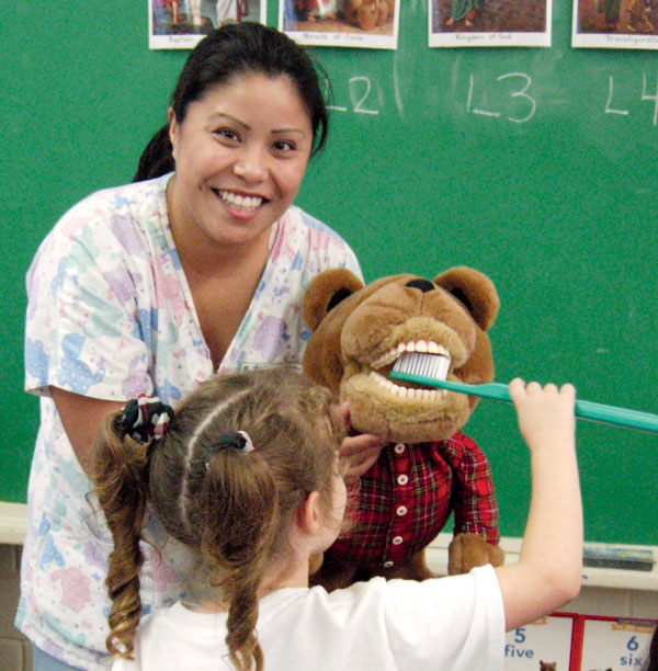Dental hygiene student Martha Rayas teaches Head Start preschoolers how to properly brush their teeth.
