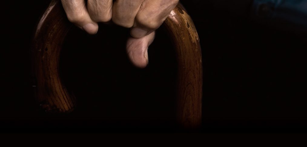 elderly hand holding a cane.