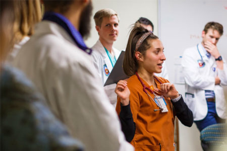 Nursing student Taylor Dramberger discusses a patient’s case with nursing and medical students, including Andrew Jeffery who is behind her to the left, during a faculty-led presentation before the weekly clinic opens to patients.