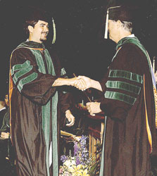 Joseph R. Becker, M.D. accepts his diploma from his father, Richard A. Becker, M.D., FACP