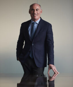 A photo of Dean Peter Loomer reflected in the table in front of him.