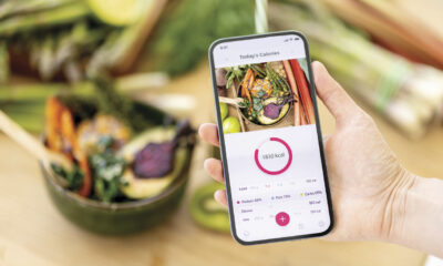 A person holds a phone with a health app open in front of a salad.