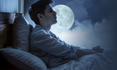 Graphic of man sleeping up right in bed with the moon behind him.