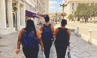 Three nursing students wearing heavily stuffed backpacks walk downtown San Antonio.